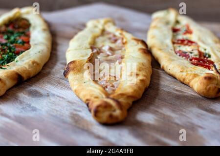 Un closeup di appetitosa varietà di pide flatbread ripieni di condimenti su una superficie di legno Foto Stock