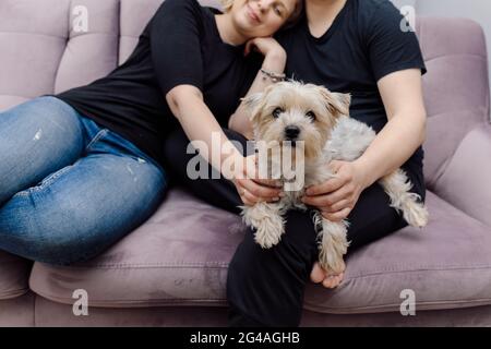 La giovane famiglia si rilassa sul divano nel soggiorno con Yorkshire Terrier Dog.Concept di famiglia felice. Felicità e amore. Comprensione reciproca e tende Foto Stock