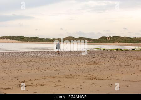 Beadnell, Northumberland, Regno Unito. 20 Giugno 2021. Gli escursionisti e i joggers del cane sono i primi ad arrivare su una spiaggia altrimenti vuota in Beadnell Bay, Northumberland, in una mattina opaca. Il tempo più luminoso è previsto più tardi questo pomeriggio. Peter Lopeman/Alamy Live News Foto Stock