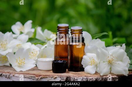 Olio essenziale e fiori di gelsomino su sfondo di legno. Procedure cosmetiche. Foto Stock