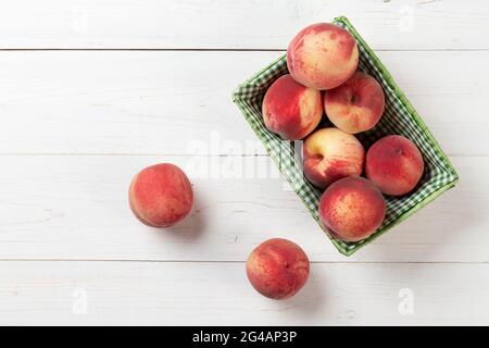 Pesche fresche e mature in un cestino su sfondo bianco di legno. Frutta deliziosa e sana. Concetto di cibo sano. Foto Stock