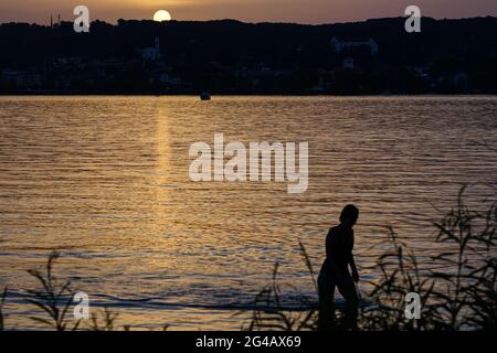 Bellissimo tramonto su un lago con una silhouette di una donna. Foto Stock