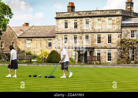 L'uomo raccoglie le ciotole nella partita locale delle ciotole del prato sul verde in Hexham Northumberland Foto Stock