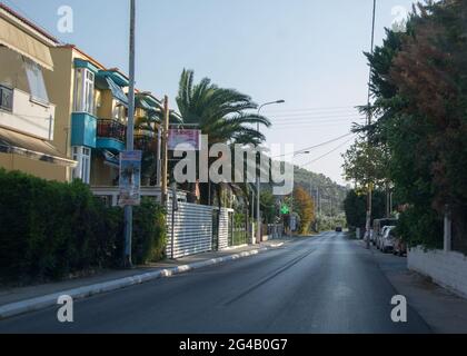 Una strada asfaltata in un villaggio, edifici e alberghi sul lato, bella montagna sullo sfondo, la natura a Thasos Foto Stock
