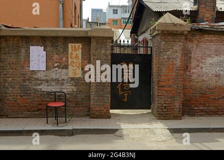 Una porta in metallo di un composto in un muro di mattoni su una strada nella città di Shenyang, in Cina, con i caratteri per nessun parcheggio scritto su di esso. Foto Stock