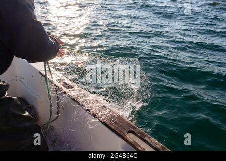 Fisherman riportando net in una barca in Bretagna Foto Stock