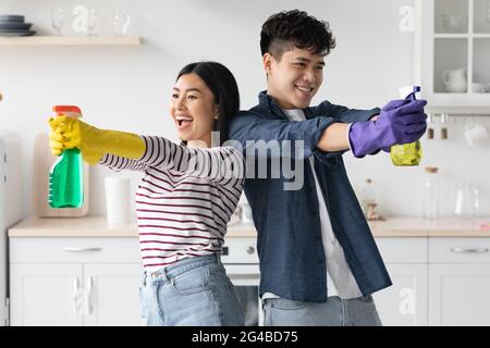 Divertente coppia asiatica con spray pulizia casa-mantenere Foto Stock