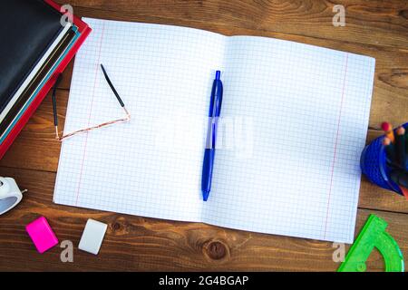 Libri, materiali per la scrittura, occhiali, notebook e sveglia sul desktop. Disposizione piatta. Concetto di apprendimento e autoistruzione. Messa a fuoco selettiva. Foto Stock