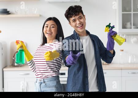 Allegro casa-custodi asiatici in posa durante la pulizia della cucina Foto Stock