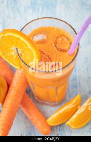 carota e succo di arancia fresco su tavola blu Foto Stock