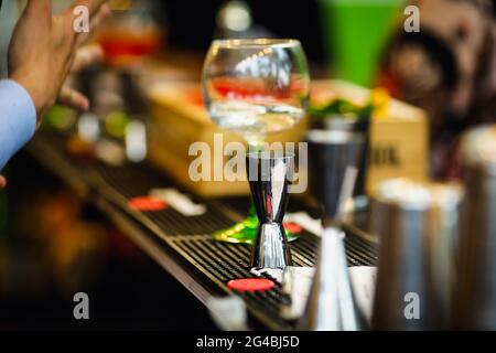 Immagine della profondità di campo poco profonda (fuoco selettivo) con jiggers di alcool di un barista sul banco di una barra. Foto Stock