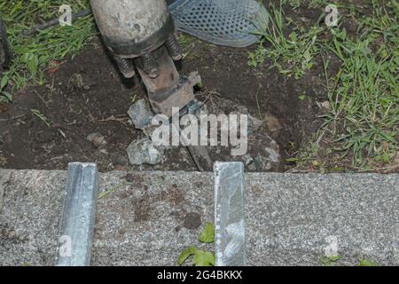 Un handyman distrugga una vecchia struttura in cemento con un martello elettrico. Primo piano. Foto Stock