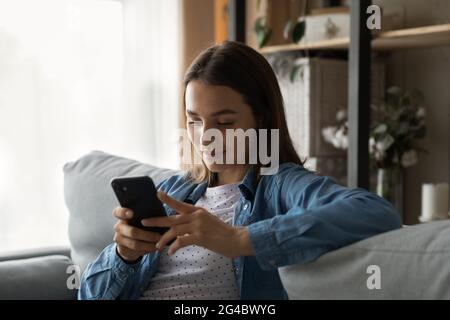 Donna giovane e rilassata che usa le applicazioni per smartphone. Foto Stock