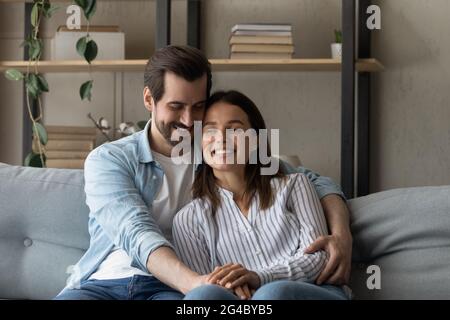 Sorridente bonding giovane coppia rilassante su un divano accogliente. Foto Stock