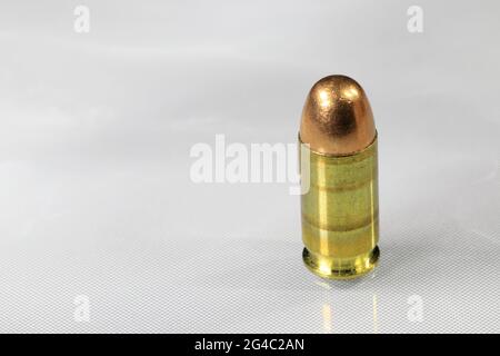 Primo piano della bullet da 11 mm o .45 acp FMJ (rivestimento completamente in metallo ) pronta per l'uso, isolare sulla superficie di riflessione bianca di fondo. Foto Stock
