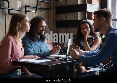 Motivati giovani dipendenti di corse miste che lavorano insieme in un bar. Foto Stock