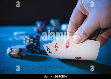La mano raccoglie le carte, tre assi, gioca il poker del casinò. Sfondo con spazio di copia Foto Stock