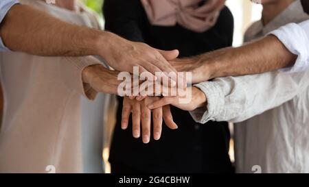 Primo piano team di dipendenti multietnici motivati che mettono insieme le mani Foto Stock