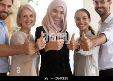 Il team dei dipendenti multietnici è felice di mostrare i pollici da vicino Foto Stock