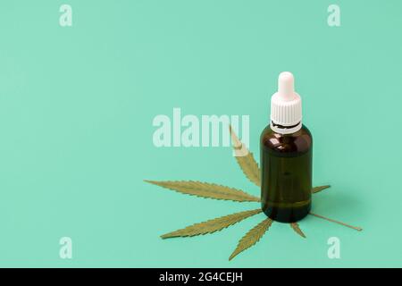 Olio di cannabis con foglie di cannabis su sfondo verde con spazio per il testo. Concetto di cannabis medica Foto Stock