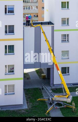 lo specialista ispeziona la facciata della casa con l'aiuto di una moderna piattaforma di sollevamento idraulico semovente mobile Foto Stock