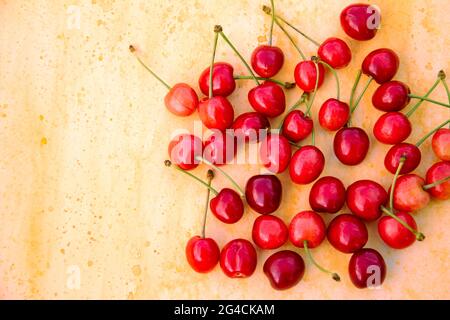 Primo piano di ciliegie rosse mature su sfondo giallo con spazio copia, vista orizzontale. Foto Stock