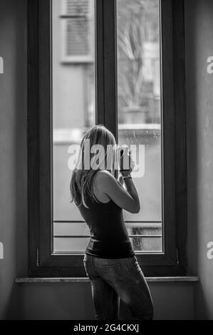 Una foto verticale in scala di grigi di una donna che scatta foto della cattedrale di Cremona, Italia Foto Stock