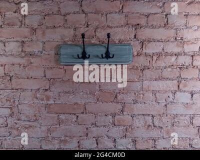 due ganci su tavola di legno grigio verniciato su una vecchia parete di mattoni fessurati e verniciati Foto Stock