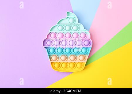 Giocattolo alla moda antistress, pop su uno sfondo arcobaleno, fidget giocattolo, vista dall'alto Foto Stock