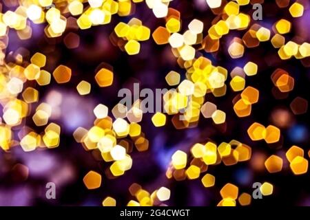 Luci dorate offuscate sfondo astratto di notte, sfocato sfondo bokeh scuro e luminoso, magico motivo giallo illuminato brillante. Foto Stock