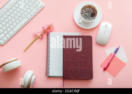 Girly desktop con Notepads cuffie per computer tazza di caffè su sfondo rosa. Spazio ufficio. Scrivania per studentessa o. Foto Stock