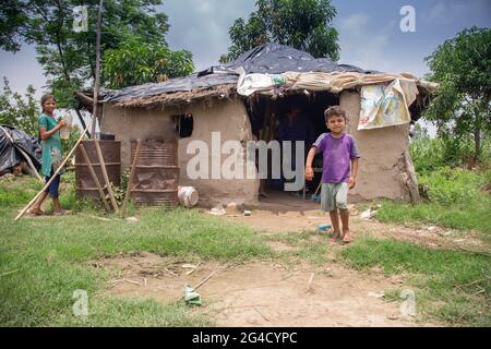 Povero ragazzo indiano in piedi alla porta di una casa di fango nella zona rurale di uttarakhand, India Foto Stock