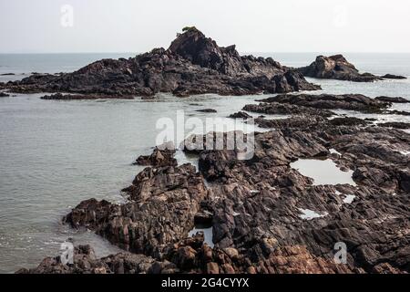 Formazione naturale di roccia nera nel mare a Om Beach, Gokarna, Karnataka, India Foto Stock