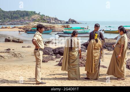 Ufficiali di polizia indiani femminili in uniformi di kaki che controllano le collane di un falchiere di spiaggia, Om Beach, Gokarna, Karnataka, India Foto Stock