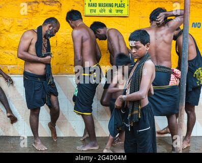 I devoti di Ayappa indossano i piedi neri di lavaggio dell'abbigliamento fuori del Tempio di Mahabaleshwar, Gokarna, Karnataka, India Foto Stock