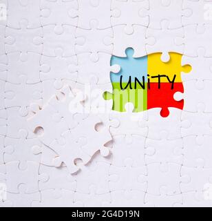Pezzi di puzzle collegati tra loro con la parola unità. Concetto di unità, sinergia, integrazione o solidarietà. Foto Stock