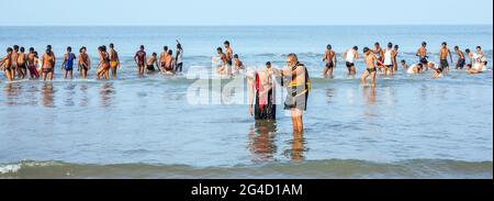 Due maschi vestiti di nero come devoti di Ayappa godendo di acqua di lettura a Gokarna Beach, Karnataka, India Foto Stock