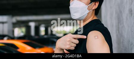 Giovane vaccinato che mostra braccia con cerotto adesivo dopo aver ricevuto l'iniezione di vaccino Covid-19 con spazio per la copia. Campagna di vaccinazione del coronavirus in bandiera panoramica Foto Stock