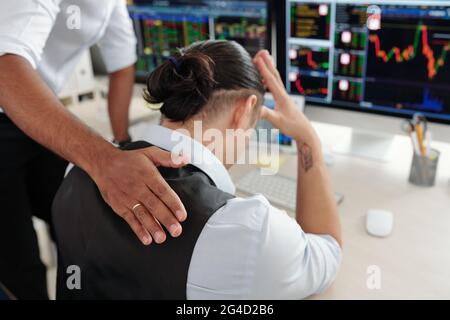 Trader pattugliando triste disperato collegue sulla parte posteriore rassicurandolo dopo che ha fatto gli investimenti difettosi Foto Stock