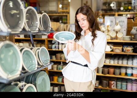 Giovane donna che sceglie nuovi piatti in negozio Foto Stock