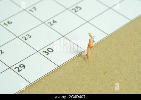 Foto di personaggi giocattolo in miniatura. Programma di viaggio concetto, uomini in piedi davanti al calendario. Foto immagine Foto Stock