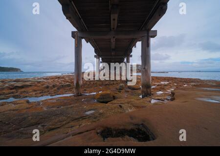 Sotto un ponte di legno a la Perouse Sydney Australia in un pomeriggio nuvoloso di pioggia scura Foto Stock