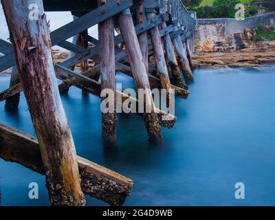 Sotto un ponte di legno a la Perouse Sydney Australia in un pomeriggio nuvoloso di pioggia scura Foto Stock