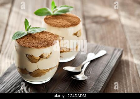 Dessert classico Tiramisu in un bicchiere su una tavola di legno in una giornata di sole. Foto Stock