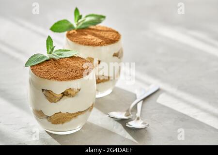 Dessert classico Tiramisu in un bicchiere su un tavolo in una giornata di sole. Foto Stock