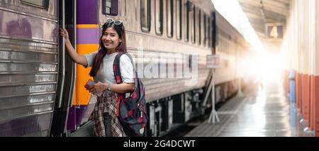 Attrazione ritratto donna asiatica a bordo di un treno alla stazione ferroviaria per viaggiare in estate. Concetto di viaggio Foto Stock