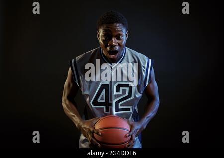 Il giocatore di basket aggressivo si pone con la palla Foto Stock