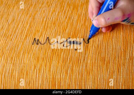 La mano dei bambini disegna un pennarello blu sulla tappezzeria del divano Foto Stock