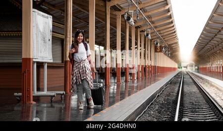 Ritratto viaggiatore assia donna a piedi e attende treno sulla piattaforma ferroviaria. Foto Stock