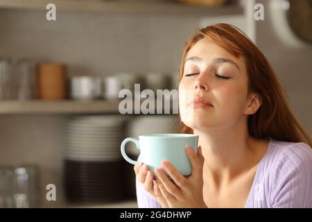 Donna rilassante bere caffè dalla tazza in cucina Foto Stock